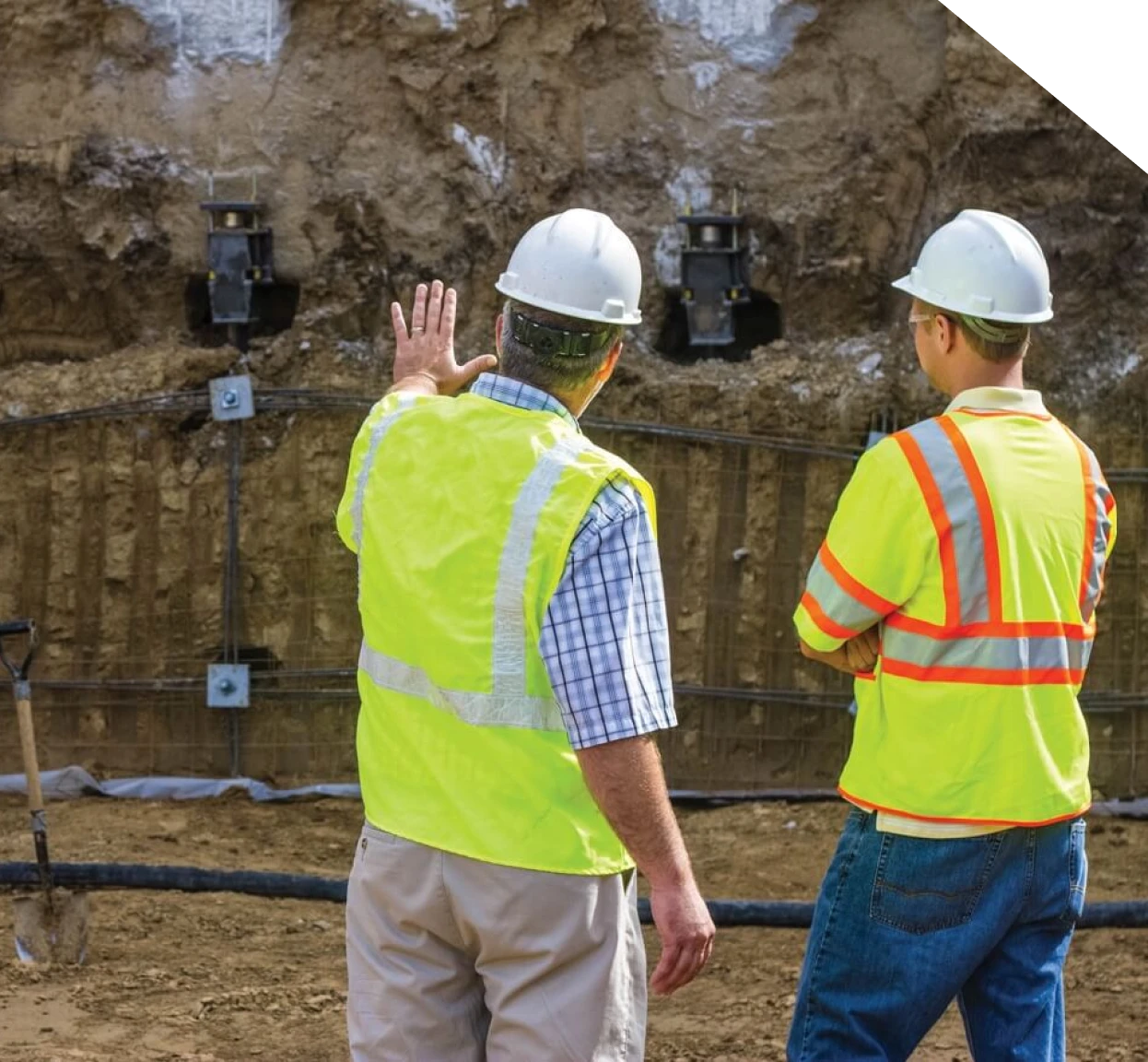 Two commercial repair professionals evaluating an excavated foundation wall and structural support system in Fort Mill, SC.