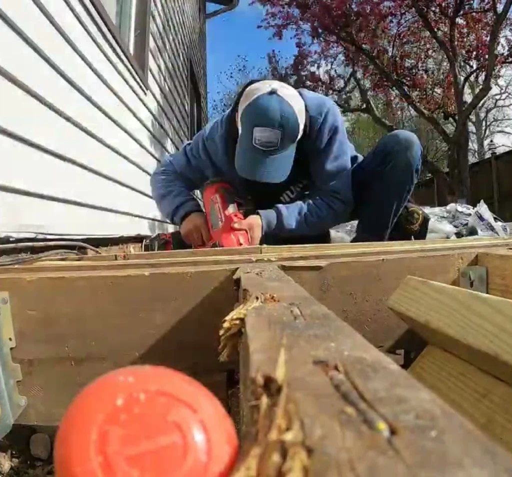 Technician cutting replacement wood for crawl space floor joist repair in Fort Mill, NC