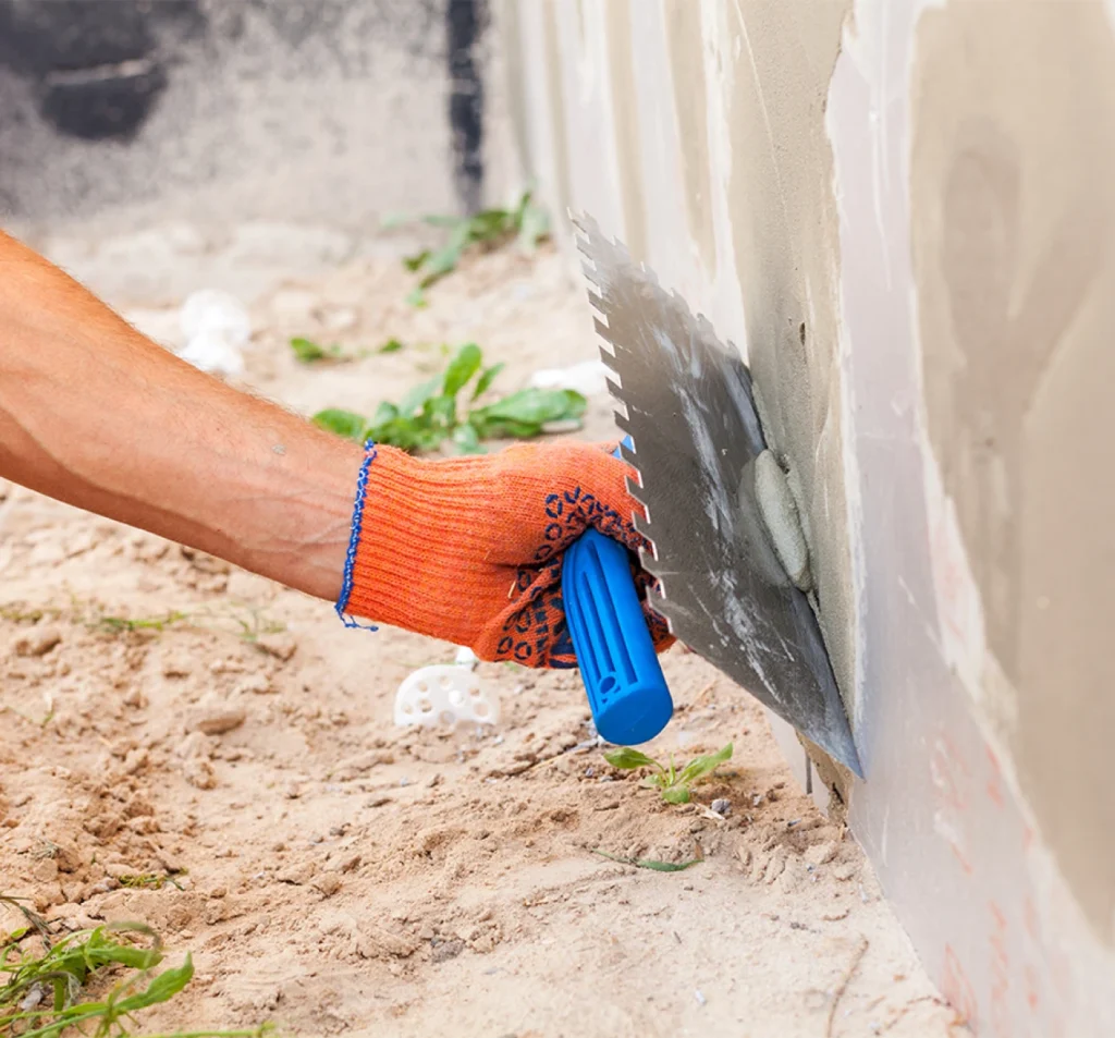 Technician applying repair mortar to a foundation wall in Fort Mill, SC
